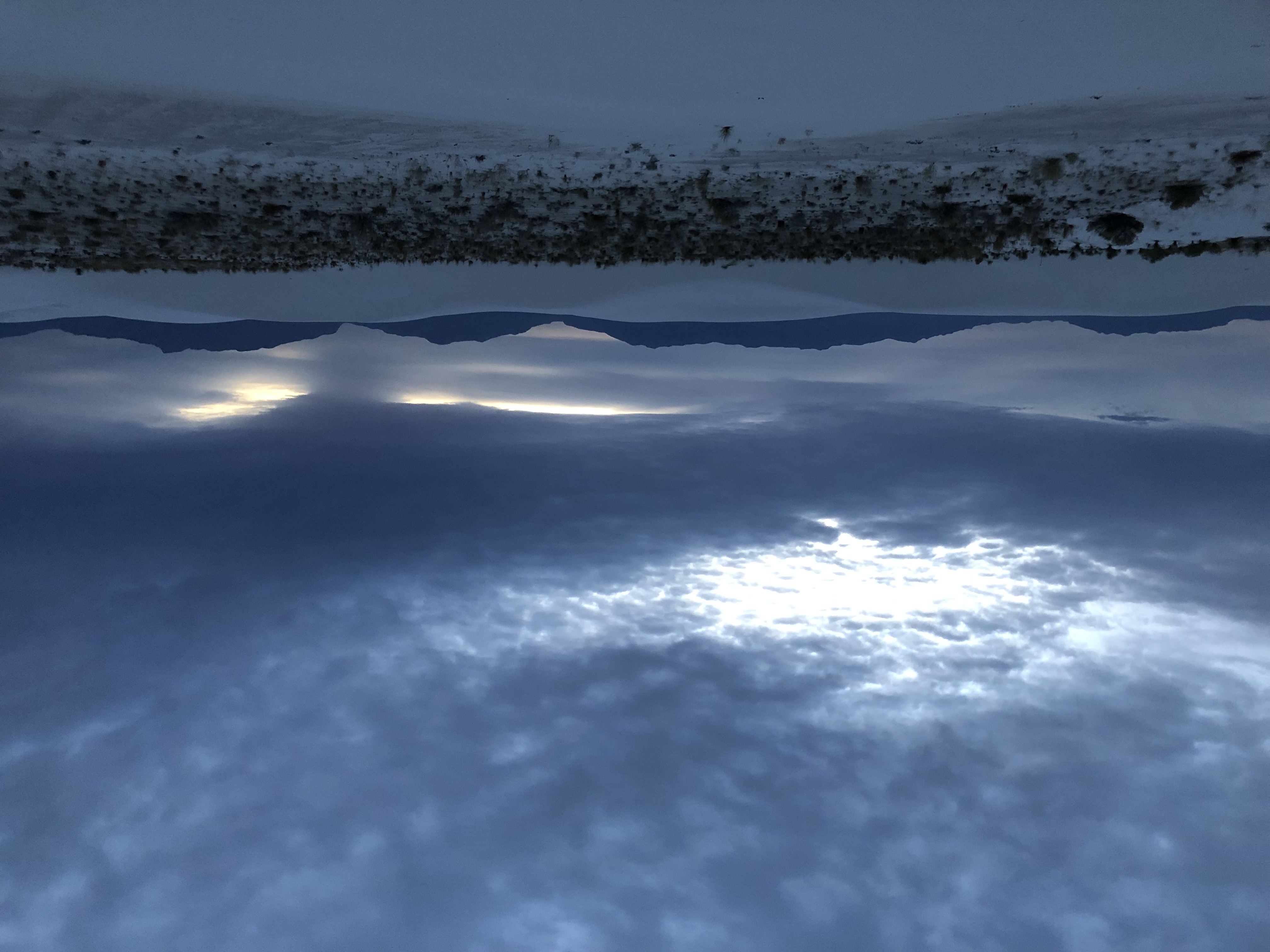 An inverted, mirror-like photo of the dunes and sky at White Sands National Park at dusk.